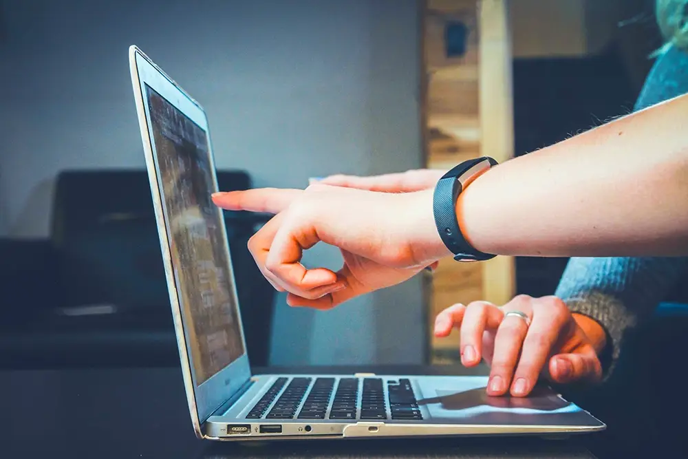 hands pointing at computer screen from side view