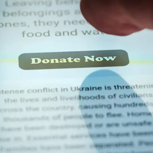 person tapping donate button on website on smartphone