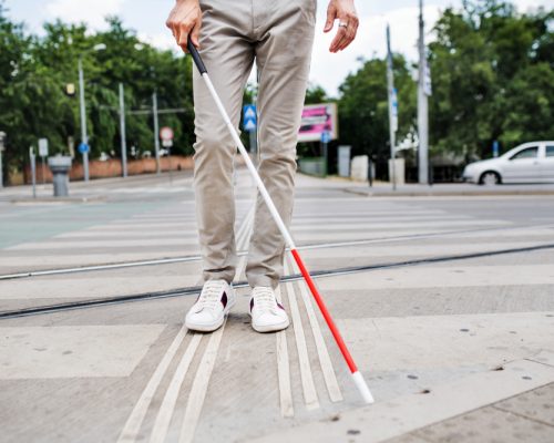 Midsection,Of,Young,Blind,Man,With,White,Cane,Walking,Across